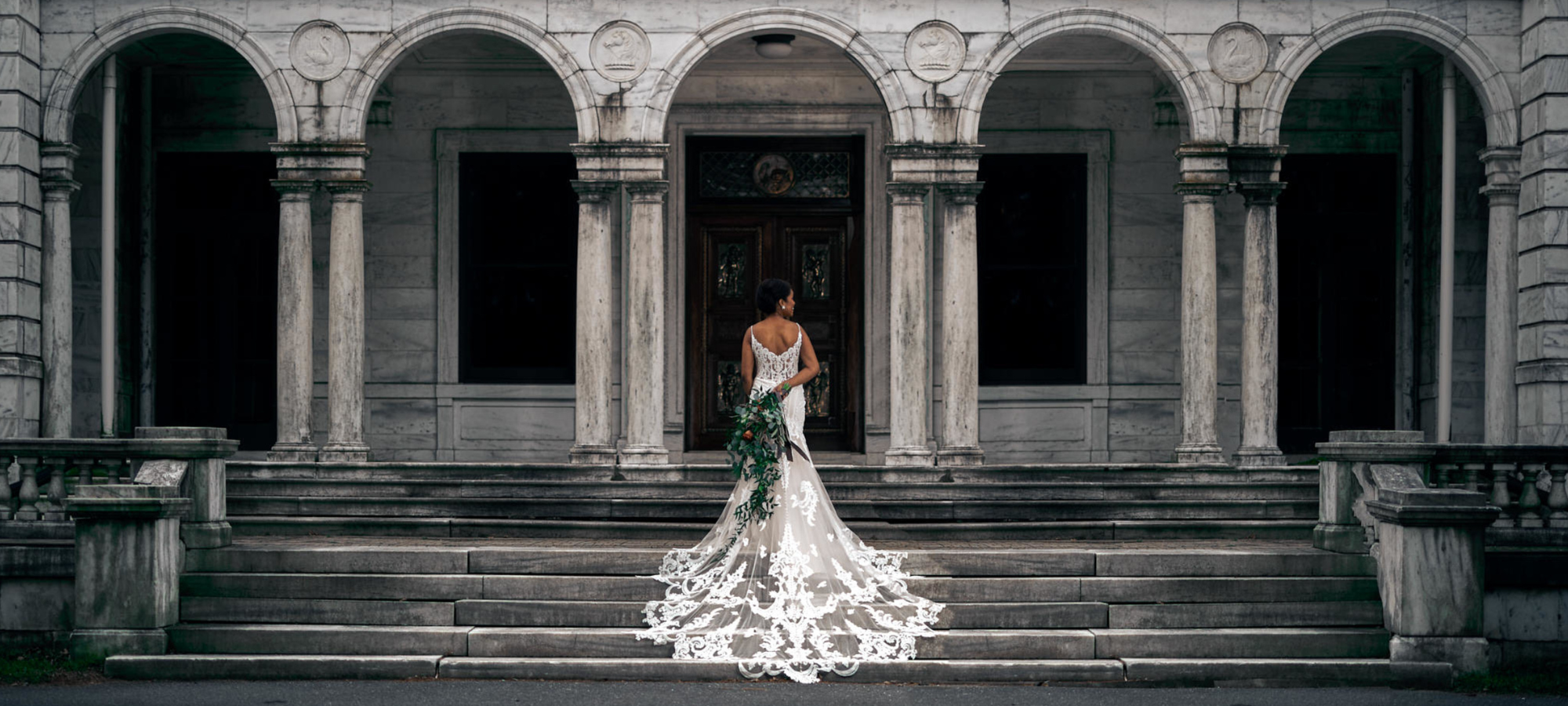 back of a stunning lace wedding dress with long train flowing over steps